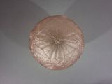 underside view of a pink glass bowl with a flower design on it