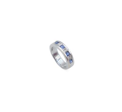 a close up of a ring with blue sapphires on a white background