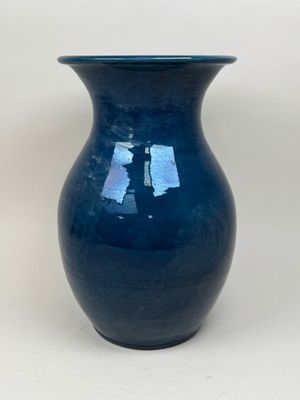 un vase bleu posé sur une surface blanche