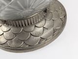 a glass bowl on a silver plate on a white surface