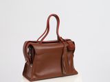 a brown handbag sitting on top of a white table