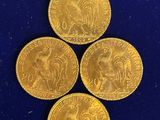 quatre pièces d'or sont disposées en triangle sur une surface bleue