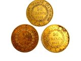 three gold coins sitting on top of each other on a white surface