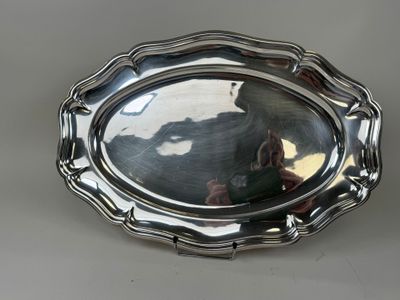 un plateau ovale en argent sur lequel se reflète un homme dans le miroir