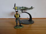 une figurine représentant un homme debout à côté d'un modèle réduit d'avion