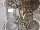 une plaque métallique posée au sol sur laquelle est représentée une femme