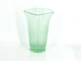 a green glass vase sitting on a white surface