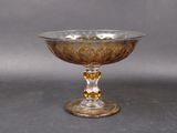 a glass bowl on a pedestal on a gray surface