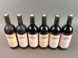 six bottles of wine lined up in a row on a table