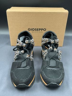 a pair of black and gold sneakers with a box in the background