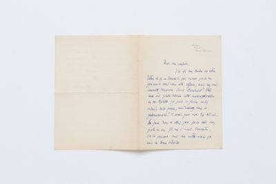 un livre ouvert, sur lequel est posée une lettre manuscrite, posé sur une table