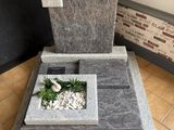 une fontaine en pierre avec une plante à l'intérieur, posée sur un sol carrelé