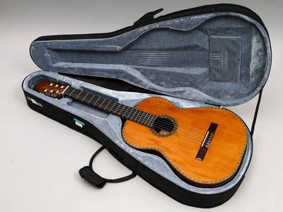 une guitare dans un étui, posée sur une surface blanche
