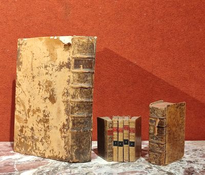 trois livres posés sur une table, avec un mur rouge en arrière-plan
