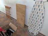 a room with a ironing board, a chair, and other items in it