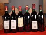 six bottles of red wine are lined up on a table