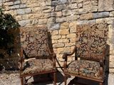 two chairs sitting next to each other in front of a stone wall