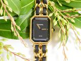 a gold and black watch sitting on a gold chain