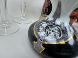 a black and gold vase with a picture on it next to wine glasses