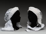 une paire de têtes de mannequin noires ornées de volants blancs et d'un bonnet blanc