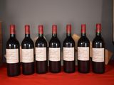 six bottles of red wine are lined up on a table