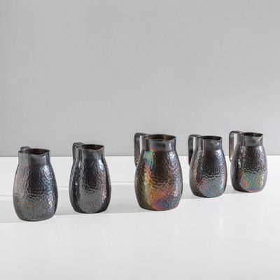 quatre vases noirs sont alignés sur une surface blanche