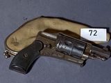 un vieux revolver muni d'une étiquette, posé sur une table