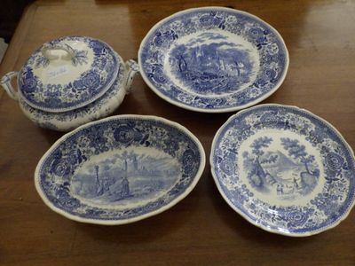 four blue and white plates and a bowl sitting on a table