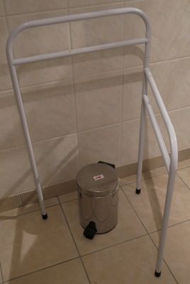 des toilettes avec un cadre métallique, à côté d'une poubelle
