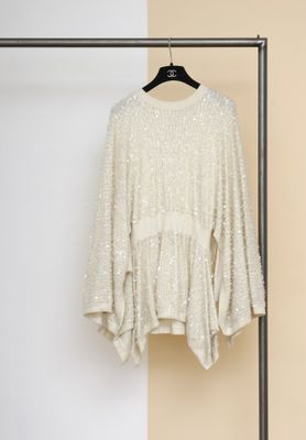 une photo d'un pull blanc suspendu à un portant