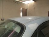 une voiture blanche garée dans un garage, avec un chien assis dessus