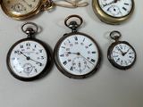 many different types of pocket watches displayed on a table