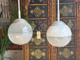 two lamps that are hanging from the ceiling above a cabinet