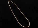 a gold necklace with a chain on a black background