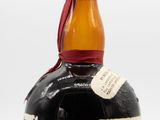 an old bottle of liquor sitting on top of a white surface