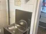 a stainless steel sink in the corner of a bathroom