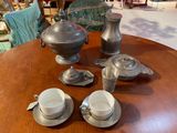 four cups and saucers on a table with a teapot
