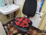 a black chair with a red ladybug on it in a bathroom