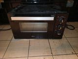 a small oven sitting on a tiled floor in a kitchen
