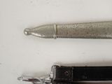 a silver pen and a black belt on a white surface