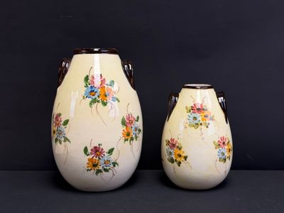 deux vases blancs décorés de fleurs, posés sur une table