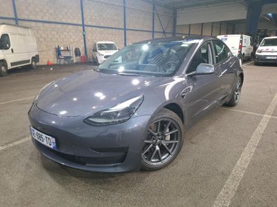 La Tesla Model 3 est garée sur un parking aux côtés d'autres voitures