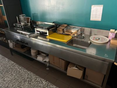 une cuisine équipée d'une cuisinière, d'un évier, d'un micro-ondes et d'autres objets posés sur le plan de travail