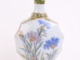 a white vase with blue flowers on it on a white background