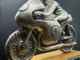 une statue représentant un homme à moto, posée sur un socle en marbre