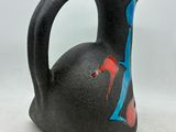 a black vase with a red and blue design on it