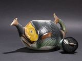 a teapot with a fish on it next to a ball