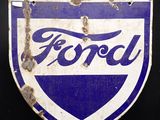 un ancien écusson Ford bleu et blanc sur fond noir