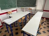 tables and chairs in a classroom with a blackboard and a chalkboard