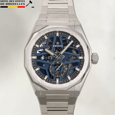une montre en argent avec un cadran bleu sur fond blanc